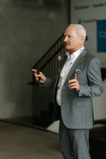 Mann steht auf der Bühne und spricht zum Publikum